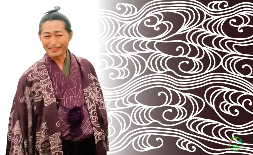 流水文様の背景の横に、流水文様の衣装を着た平賀源内（ドラマの登場人物）が立っている様子