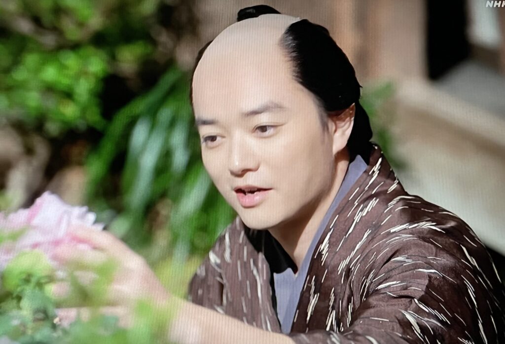 江戸時代に流行した「雨絣文様」。二色以上の絣糸で不規則に降る雨を表現し、五穀豊穣の願いが込められた伝統的な模様の衣装を着る歌麿。
