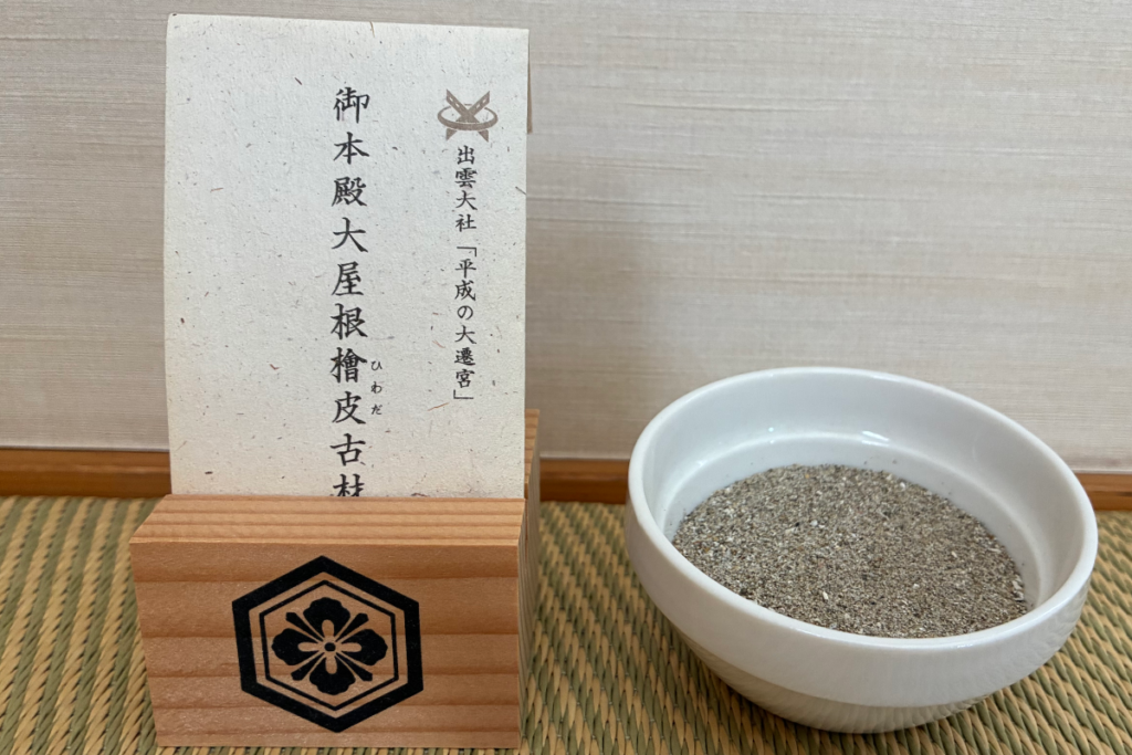出雲大社御本殿の大屋根檜皮古材(ひわだこざい)を用いたお守り(二重亀甲剣花菱の神紋入り)と、素鵞社で授かった御砂を入れた小鉢